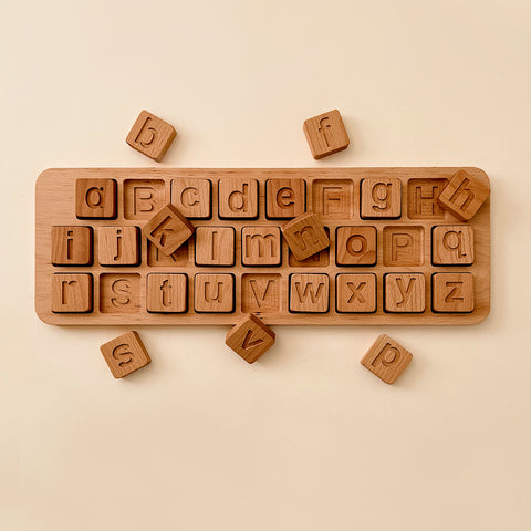Extra Large Uppercase & Lowercase Alphabet Puzzle on a light beige surface, featuring lower case letters scattered around a rectangular board containing indented spaces for each letter.