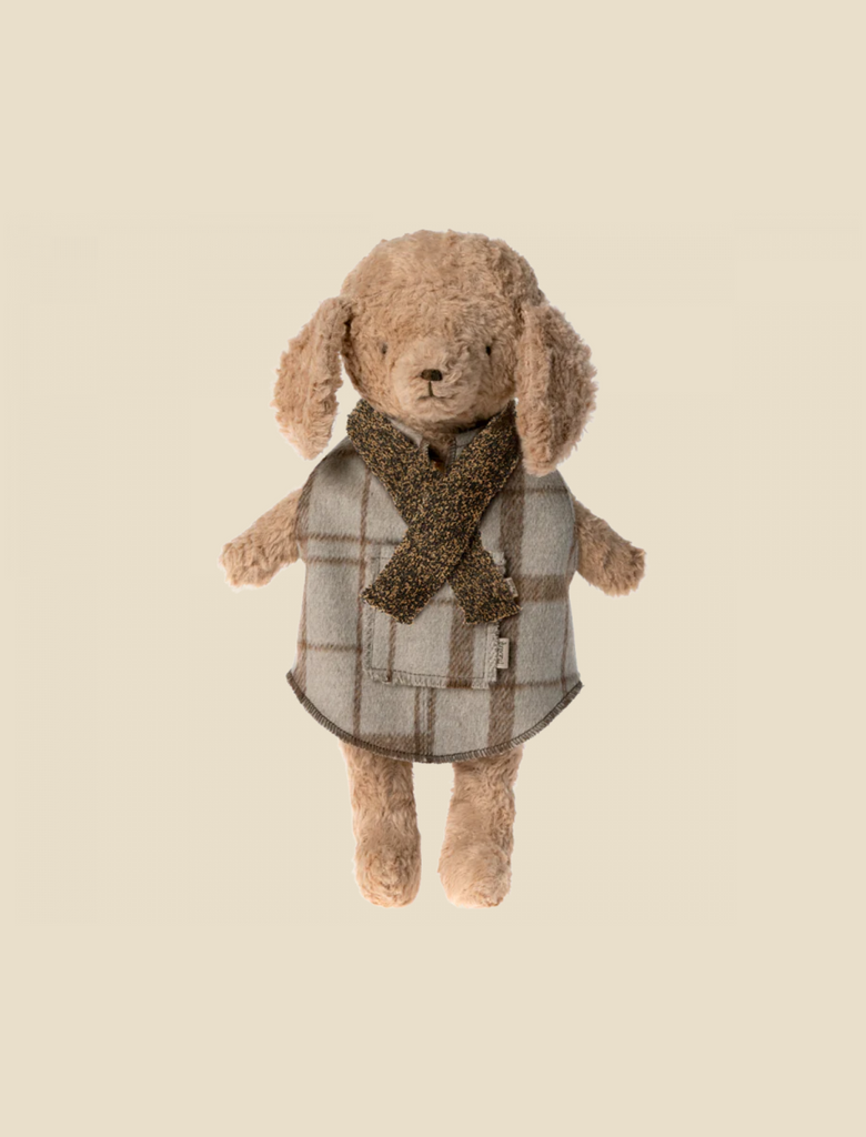A Maileg Puppy - Knitted Scarf wearing a checkered coat and a knit scarf. The puppy has soft, light brown fur and floppy ears. The outfit, resembling something from a stylish dog wardrobe, exudes a cozy and winter-ready feel.
