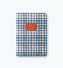An Assorted Set of 3 Schoolhouse Notebooks, each featuring a blue and white checkered cover with a red “NOTEBOOK” label centered on the front, lay-flat binding for easy writing, displayed against a plain light gray background.
