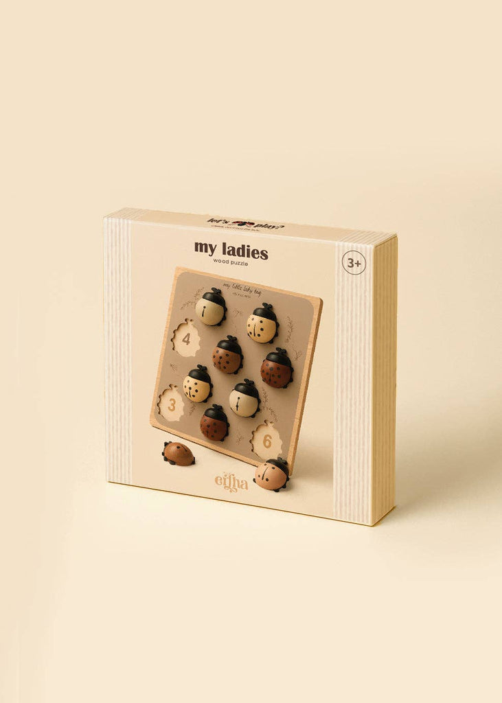 A beige box labeled “My Little Lady Bug Wooden Puzzle” contains a wooden peg puzzle featuring six numbered ladybug pieces (1–6). Designed for ages 3 and up, this Montessori-inspired counting toy encourages early number recognition and fine motor skills.