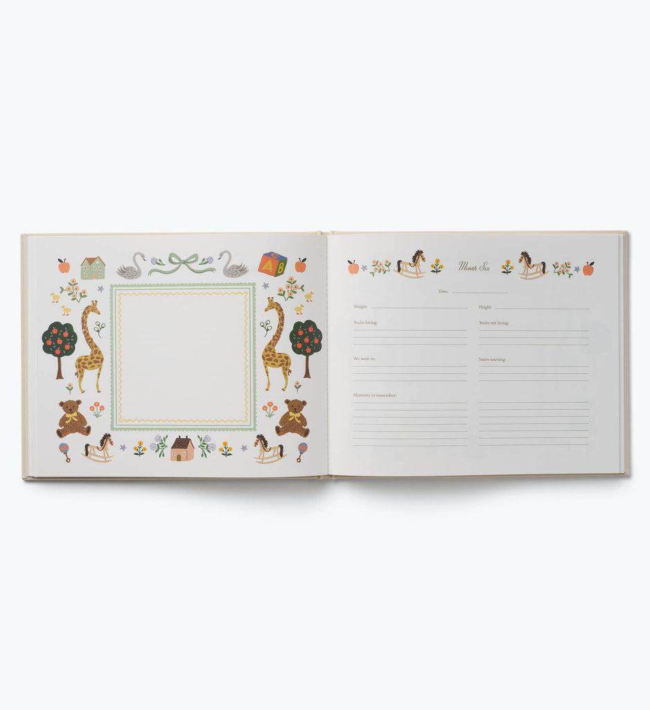 The Storybook Embroidered Baby Book features an open layout with an illustrated animal and nature border on the left page, while the right page offers lined sections for writing memories and notes, all set against a crisp white background.