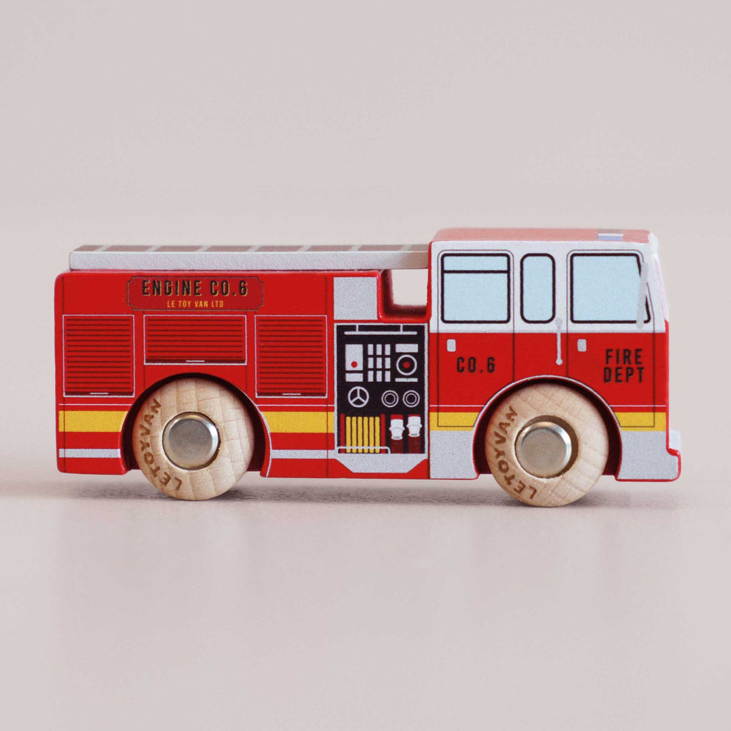 The No. 44 GT270 Quinn, made in England, is a wooden toy fire truck adorned with red, yellow, and gray details and labeled “FIRE DEPT” and “ENGINE CO. 6.” Perfect for imaginative adventures, this wooden fire engine features durable wooden wheels and printed control panels. Shown in profile on a neutral background, it’s ready to inspire heroic rescue missions at playtime.