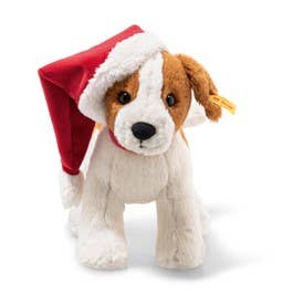 The Steiff Snuffy Puppy Dog Plush features brown and white fur with a red Santa hat playfully tilted to one side. It has black eyes and a stitched nose, creating a festive appearance.