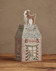 The Coral & Tusk Home for the Holidays Tissue Box Cover is a decorative, embroidered house featuring a deer on the roof, brick walls, festive garlands, owls, and a door—shown on a wooden surface with a plain background.