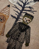The Coral & Tusk Full Moon Masquerade Pillow features embroidered Halloween figures—a bear in stripes and a person in a dark costume by a blue tree—making it the perfect festive decor.
