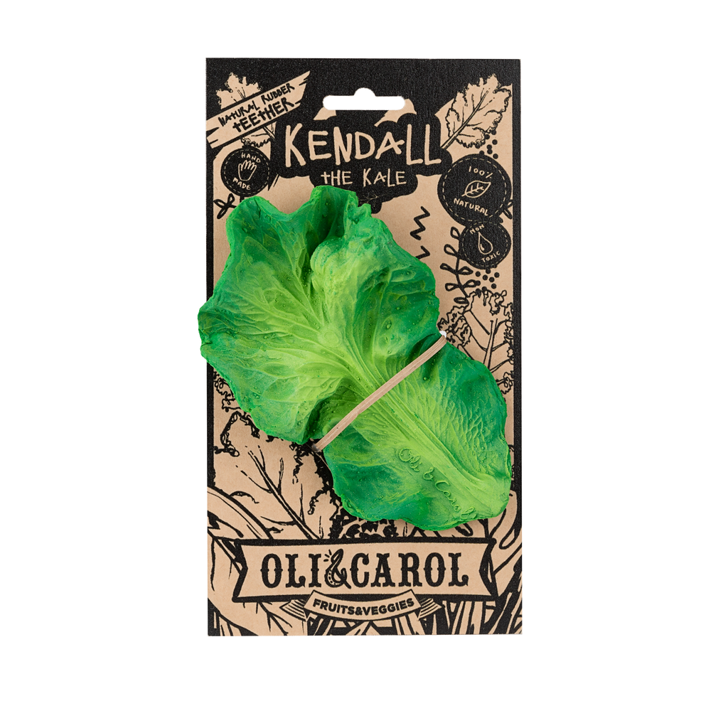 Kendall the Kale Teething Toy by Oli & Carol is a green, vegetable-shaped baby toy secured with a rubber band on cardboard packaging featuring black illustrations and text promoting fruits and veggies.