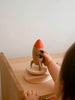 A child holds the Sabo Concept Rocket with Bear—a small wooden space toy with a red tip and a bear inside, standing on a round platform—perfect for imaginative play.