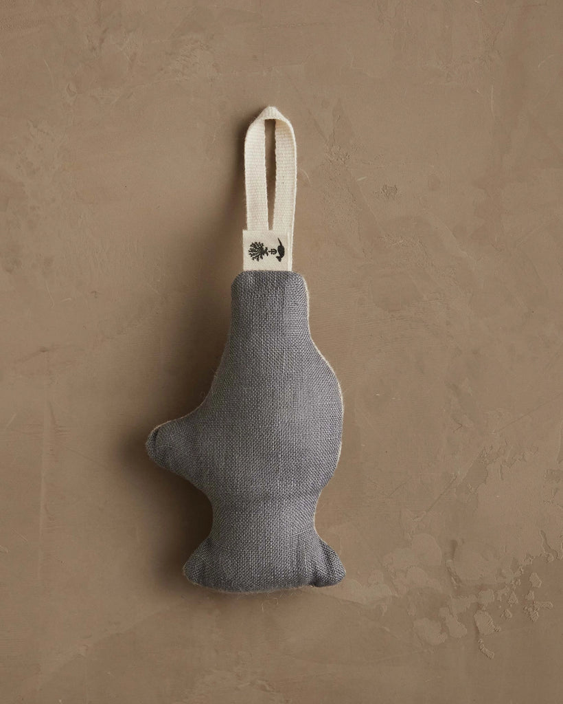 The Coral & Tusk Yeti with Candy Cane Ornament, a gray fabric ornament with a cream-colored hanging loop, rests on a textured light brown surface—perfect as a charming Christmas decoration or thoughtful gift.