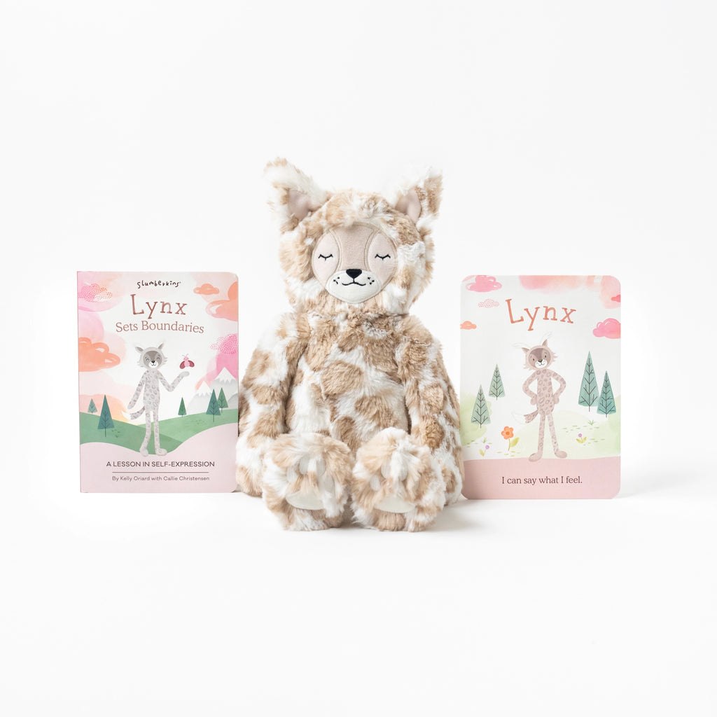 A Slumberkins Lynx Kin + Lesson Book On Self Expression plush toy sits between two children's books titled "Lynx Sets Boundaries" and "Lynx" against a white background. The hypoallergenic stuffed animal has a