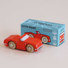A classic toy, the No. 13 GT75 Marc racing red wooden convertible with tan wheels sits in front of a blue box labeled “GT75 MARC” and “Le Toy Van,” featuring an illustration of the car, limited edition text, and proudly made in England.