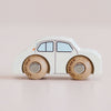 Introducing the No. 20 GT110 Rene, handcrafted in England—a small white wooden car featuring minimal blue windows, tan wooden wheels, and sturdy metal axles. Displayed on a soft pink background, it’s perfect for imaginative play and brings timeless charm to any classic toy collection.