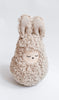 A handmade musical roly poly - Bunny shaped like a sleepy bunny with long ears, covered in soft, curly beige fur, against a plain white background. Its face features closed eyes with a peaceful expression and emits gentle musical sounds.