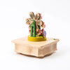A Ferris Wheel Fairy Music Box made from sustainably sourced wood, featuring a rotating floral design atop a hexagonal base, decorated with small, colorful beads and detailed cutouts, set against a clean