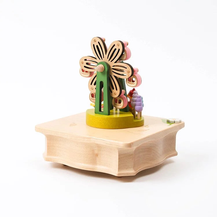 A Ferris Wheel Fairy Music Box made from sustainably sourced wood, featuring a rotating floral design atop a hexagonal base, decorated with small, colorful beads and detailed cutouts, set against a clean