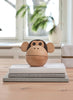 A Spring Copenhagen The Monkey Bowl, designed by Mencke&Vagnby, featuring a round head and ears, sitting on a white cloth in a bright room with blurred background of a window and plants.