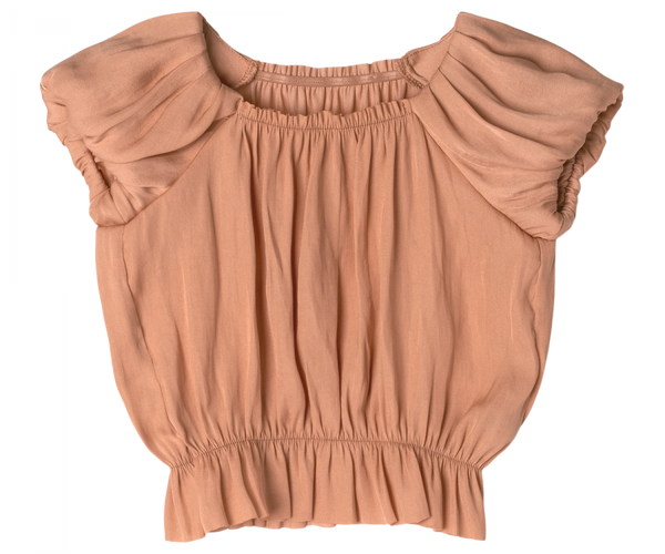 An apricot-colored, short-sleeve blouse with gathered fabric at the shoulders and an elastic band at the waist. The top has a loose fit and a round neckline, creating a ruched and textured appearance, crafted from exclusive materials found only in your Magical Wardrobe – introducing the Maileg Princess Blouse - Melon (Final Sale).
