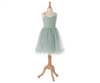 A light green, sleeveless tulle dress on a wooden mannequin stand. The dress features delicate shoulder straps and a fitted bodice, transitioning into a full, layered tulle skirt made of exclusive materials. It looks straight out of a Maileg Princess Tulle Dress - Mint. The stand has a sleek, light wood finish with an elegant design.