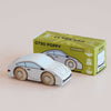 A classic wooden toy car with painted details sits before a green and yellow box labeled “No. 16 GT90 Poppy,” which features an illustration of the same wooden sports car. Made in the United Kingdom, this charming collectible exudes timeless appeal.
