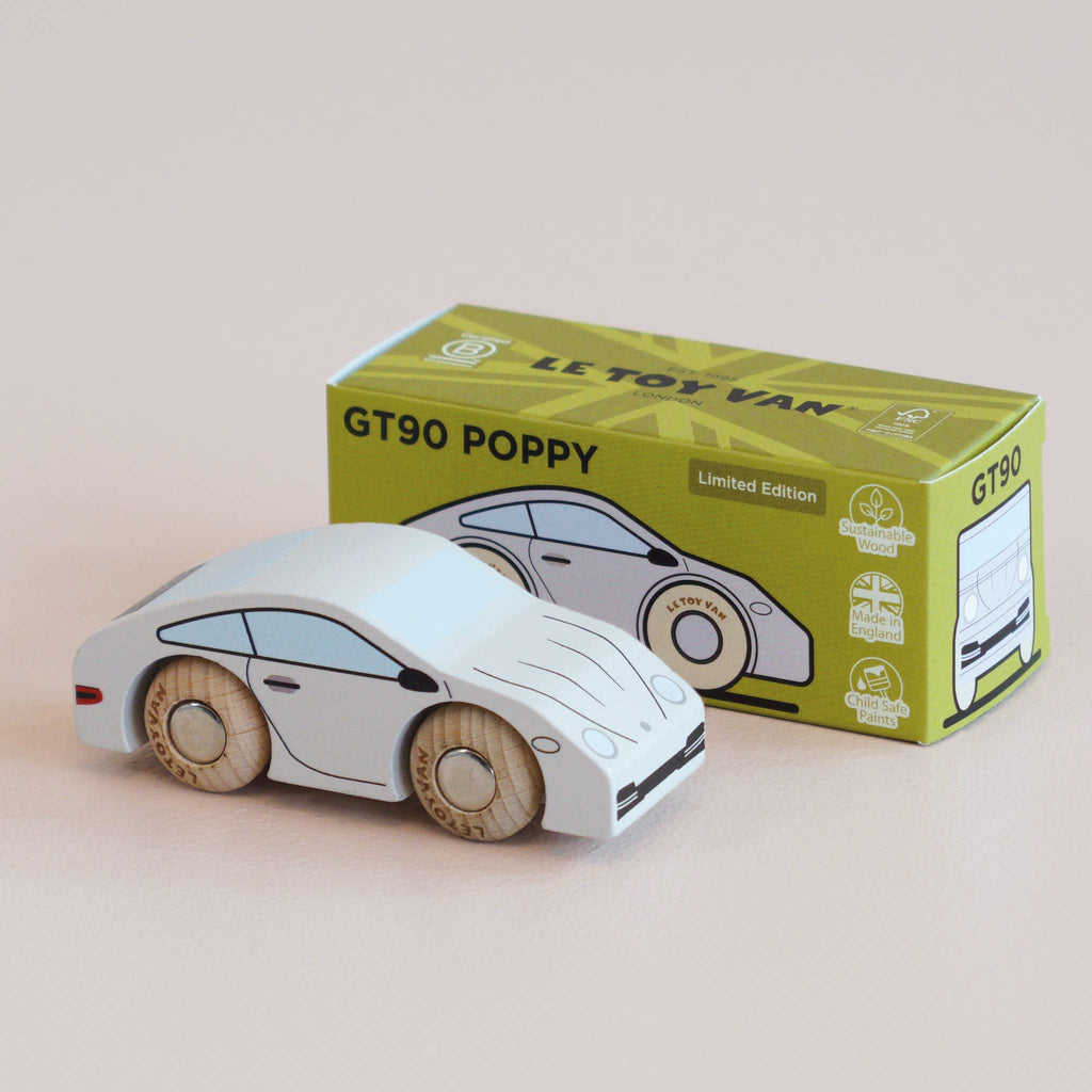 A classic wooden toy car with painted details sits before a green and yellow box labeled “No. 16 GT90 Poppy,” which features an illustration of the same wooden sports car. Made in the United Kingdom, this charming collectible exudes timeless appeal.