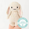 A hand holds the Cuddle + Kind Baby Bunny - Confetti, a soft, hand-knit plush toy with long ears and a smiling face. A blue "Best Toy 2022 Good Housekeeping Awards" badge appears in the corner.