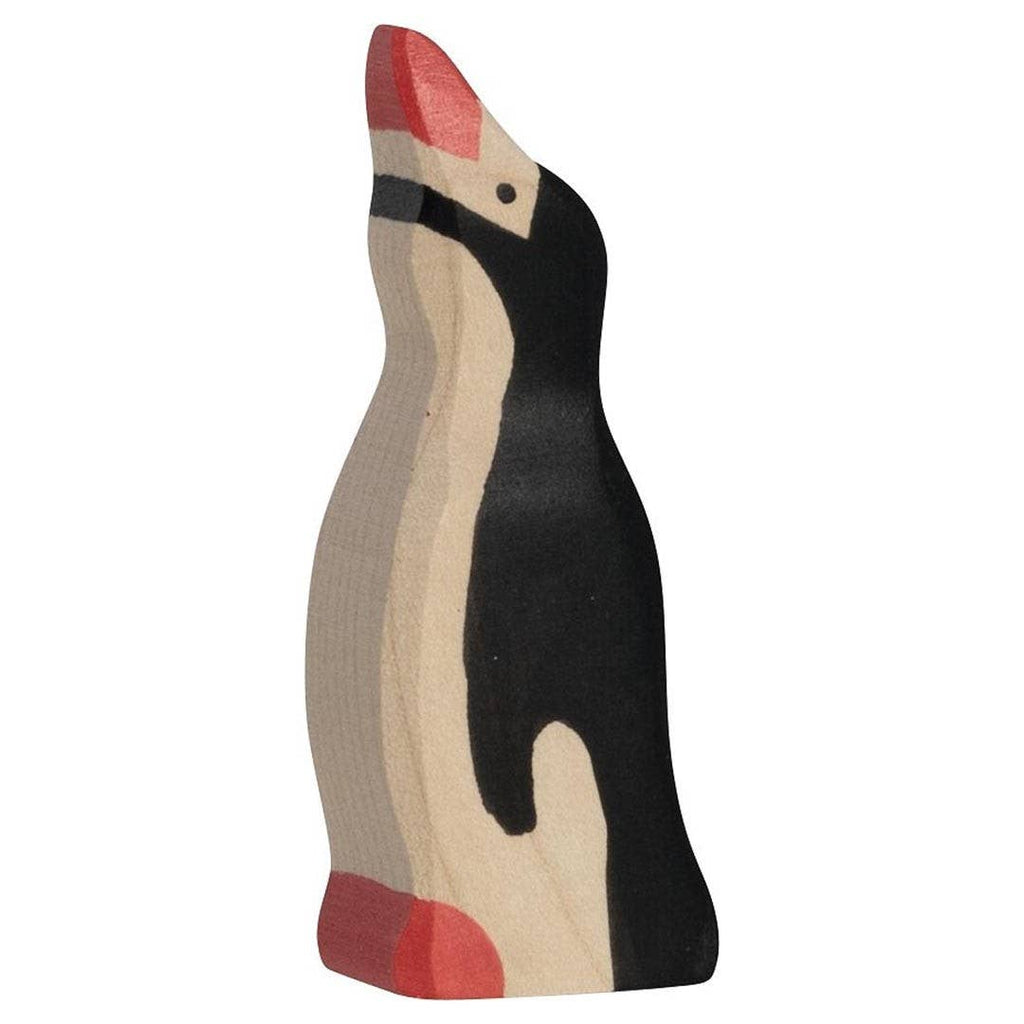 A small Holztiger Penguin figurine, featuring a raised head, handcrafted and painted in black, white, and red tones, standing upright and facing to the left.