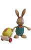 A handcrafted Collectible Dregeno Easter Figure - Rabbit With Trolley from the Erzgebirge region, depicting a rabbit with large ears and a bow tie, pulling a cart with a colorful painted egg. The background is plain white.