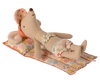 The Maileg Beach Float, Mouse - Flower is lying on a small quilted mat with a colorful flower pattern. The mouse toy features a floral pattern diaper and a flower decoration on its chest, giving it a charming look. The raft-like fabric of the mat makes it perfect for dry land play. With its eyes closed and sporting a content expression, the mouse looks as though it is relaxing or sleeping.