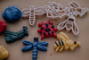 The Insect Cutter Set - Eco Playdough Tool includes colorful playdough shaped into insects and bugs, each with matching white plastic cutters—featuring a blue dragonfly, yellow bee, red ladybug, and more—all displayed on a beige surface. This sensory play set features eco-friendly tools and insect-shaped cutters for creative, hands-on fun.