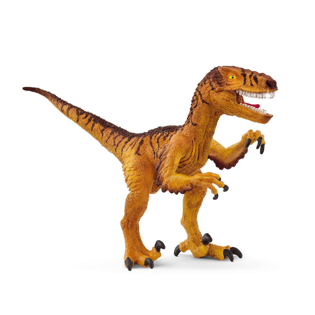 The Schleich Velociraptor dinosaur toy, designed in detailed shades of orange and brown, stands upright with its mouth open to display a movable jaw with sharp teeth and raised claws, set against a white background.