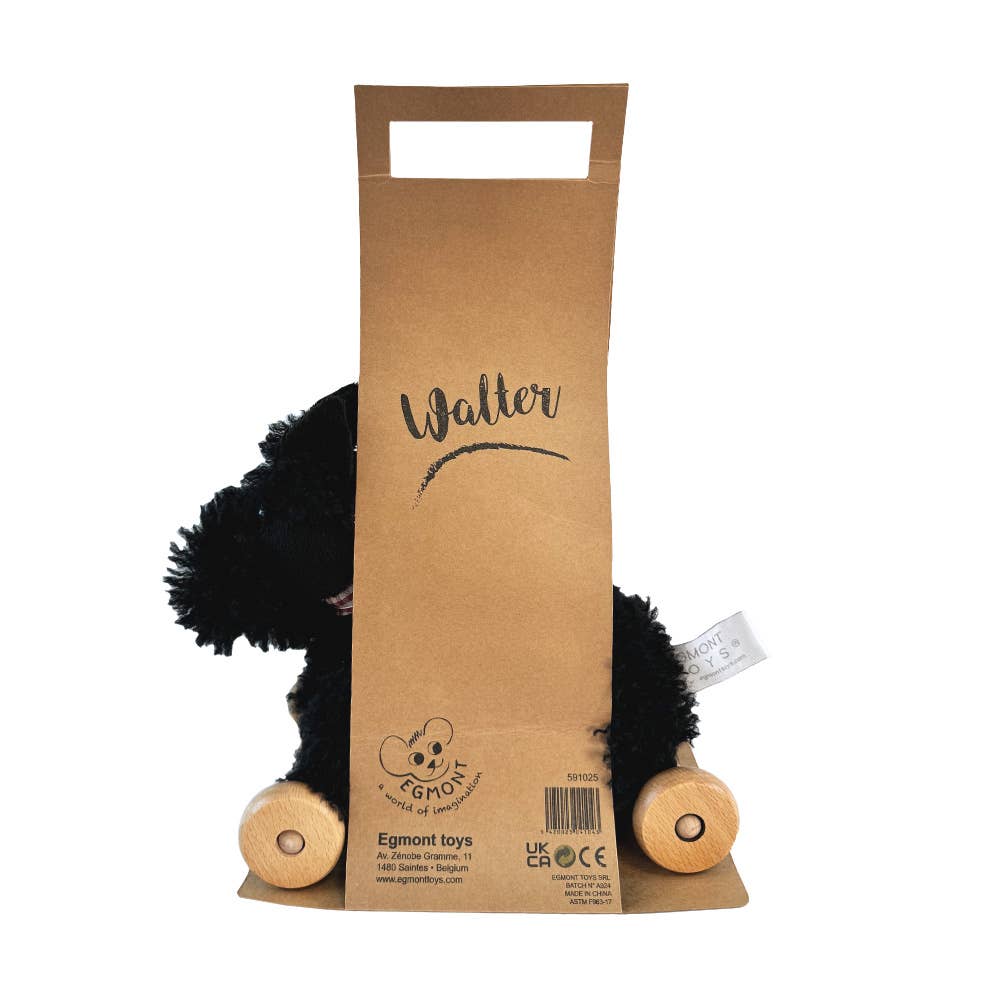 Pull-Along Walter, a black plush dog pull-along toy with wooden wheels, is partly hidden behind a brown paper bag labeled "Walter." The bag features a convenient handle cutout and a logo at the bottom, making it perfect for encouraging gross motor skills in little ones.
