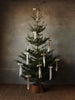 A Christmas tree decorated with multiple Ferm Living Bow Decoration - Small - Set of 2 - Natural (Organic Cotton) bows hanging from its branches.
