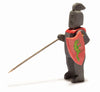 The Ostheimer Black Knight figurine stands holding a lance and a red shield emblazoned with a green dragon. Dressed in black armor, his helmet features a vertical slit for the eyes and a small crest on top. Posed in a slightly angled stance, this figure is perfect for imaginative play.