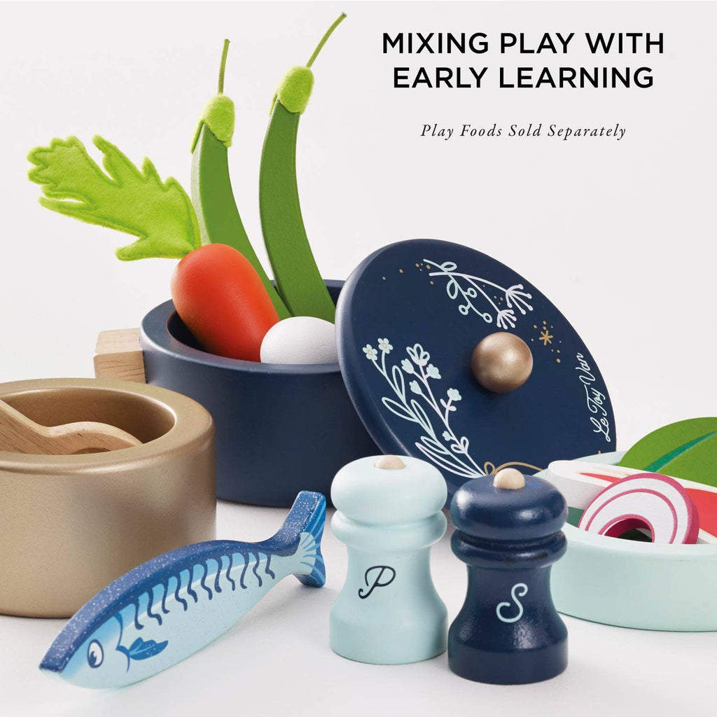 Pots & Pans Kitchen Accessories set featuring a navy pot with a lid, salt and pepper shakers, and wooden play food, with text reading “MIXING PLAY WITH EARLY LEARNING” and “Play Foods Sold Separately.”