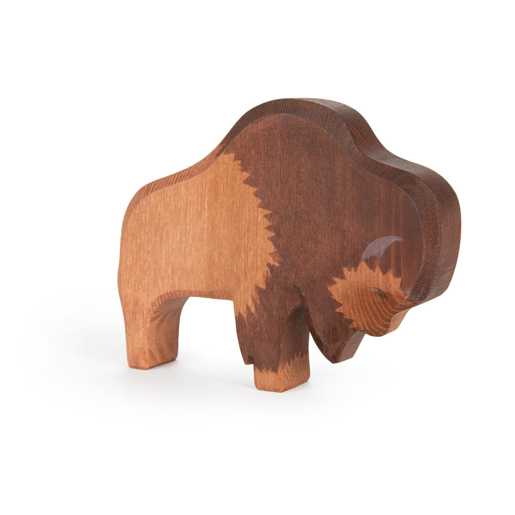 The Ostheimer Bison is a handcrafted wooden figurine with two wood tones, carved geometric patterns, and smooth, rounded edges, inspired by Ostheimer toys. It stands on a white background.