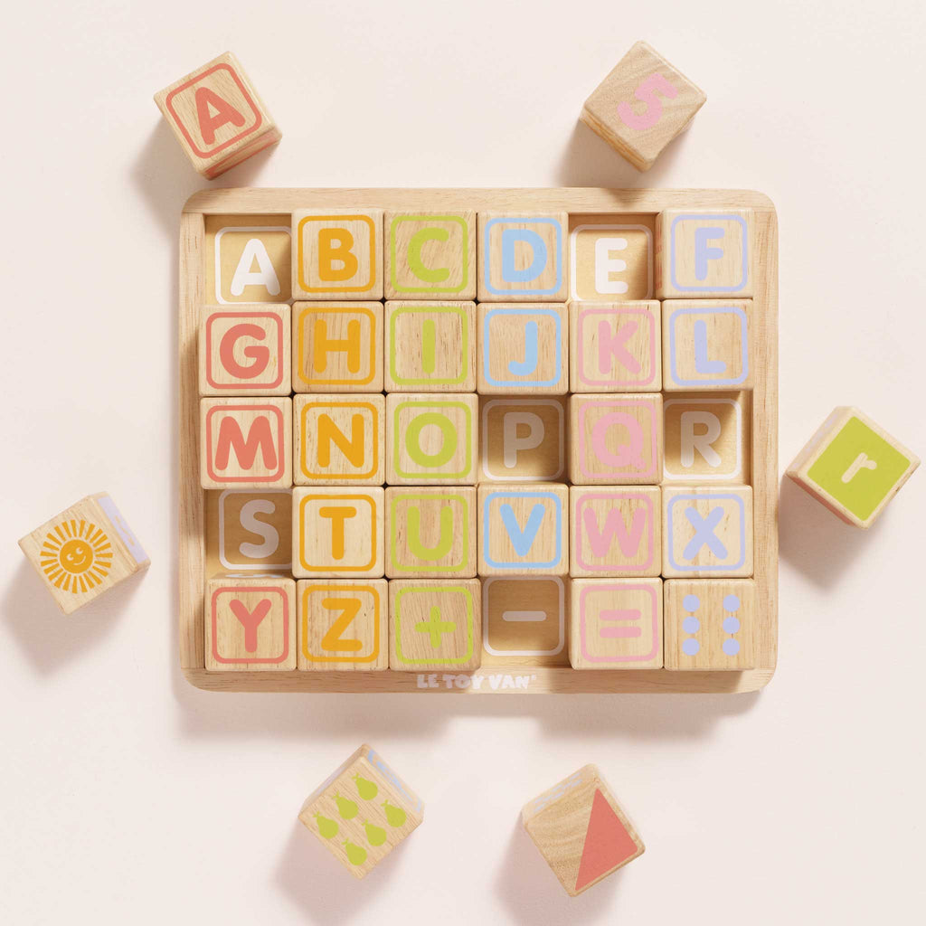 The ABC Learning Blocks (ships in one week) is a wooden puzzle board with pastel letter and shape blocks, offering toddlers a fun and educational way to learn the alphabet and patterns on a light background.