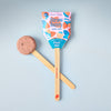 A Garden Seed Pop (Single) with a wooden stick rests on a light blue surface beside its vibrant “Plant Me!” packaging—a fun organic seed starter, ideal for any vegetable garden kit.