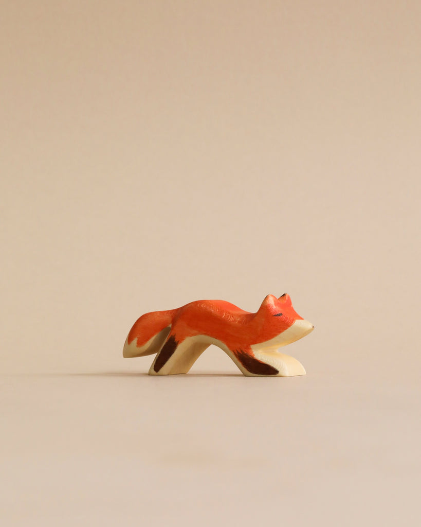 A small, handmade wooden fox figurine from the Handmade Holzwald Woodland Animals Set, depicted in a leaping pose with orange and brown details.