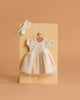 The Minikane 11" Doll Clothing | Rosana Short-Sleeved Tutu and Headband - Linen features a cream linen dress with short sleeves and a tulle skirt, plus a ribbed headband, perfect for your Minikane doll—shown on a wooden board against a beige background.
