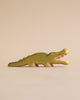 A Handmade Holzwald Crocodile on a plain beige background, standing with its mouth open, showcasing detailed carvings and a smooth green finish.