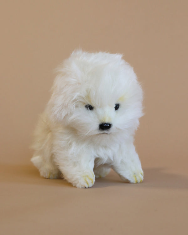 A Maltese Tea Cup Stuffed Animal with a realistic face and yellow-tipped feet stands against a light beige background.