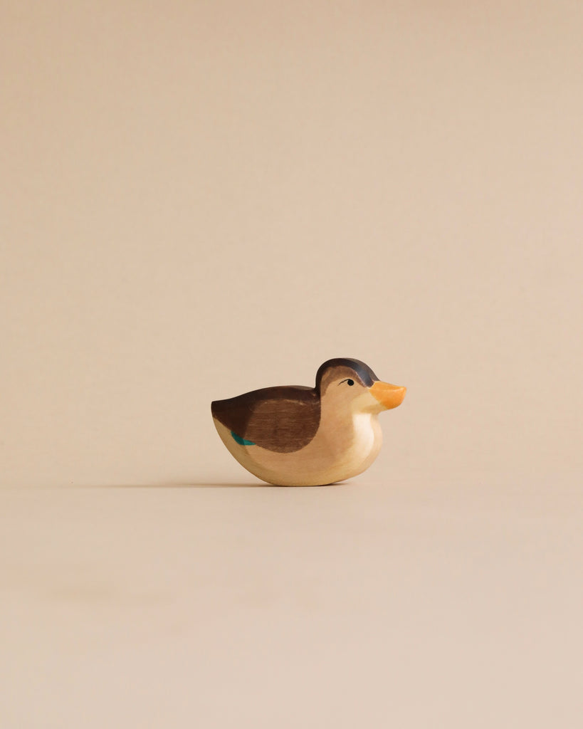 A Handmade Holzwald Swimming Duck wooden figurine with a smooth finish and painted details stands centered against a plain beige background.