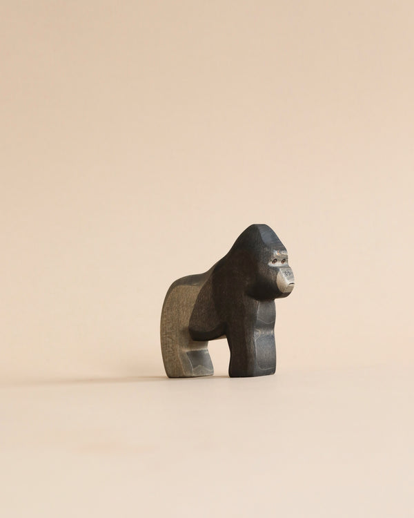 A small, Handmade Holzwald Gorilla statue standing on all four limbs, depicted in a minimalist style against a uniform light beige background.