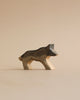 A Handmade Holzwald Wolf figurine, crafted with simple, smooth lines from high-quality wood, displayed against a light beige background. The wolf stands in profile, showcasing its distinct silhouette.