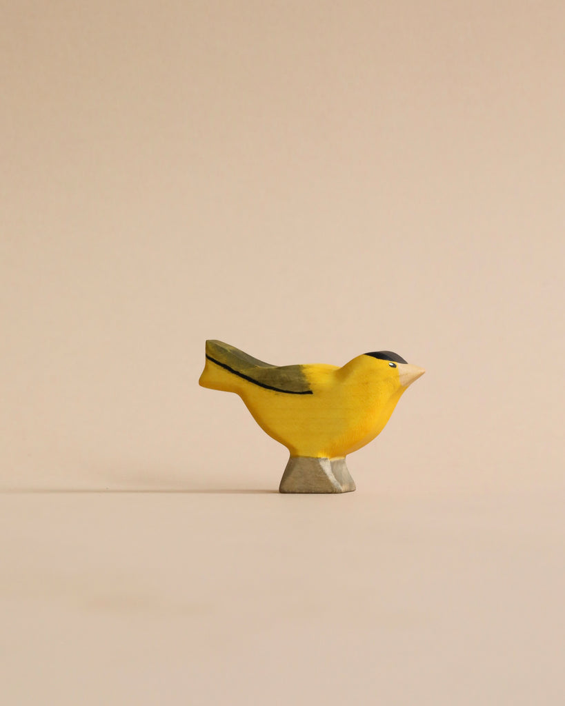 A small, Handmade Holzwald Goldfinch ceramic bird figurine with a smooth surface and subtle shading, standing on a beige background, crafted as an educational toy.