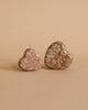 Two heart-shaped objects, including the Maileg Easter Egg with Micro Rabbit & Heart Set—one pink and one brown—are placed side by side on a matching beige background.