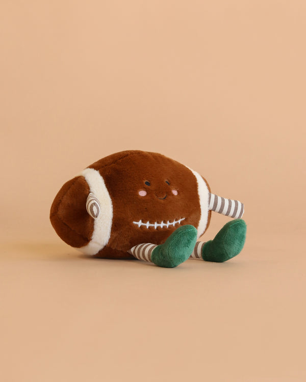 The Mon Ami - Freddie Football Plush Toy, featuring a smiling face, striped arms, and green feet, sits on a plain beige background—making it an adorable cuddle companion or a delightful gift for kids.