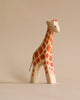 A Handmade Holzwald Giraffe - Large figurine with detailed, hand-painted orange and brown spots, standing against a plain, light beige background. This sustainable toy adds an educational dimension to any playroom.