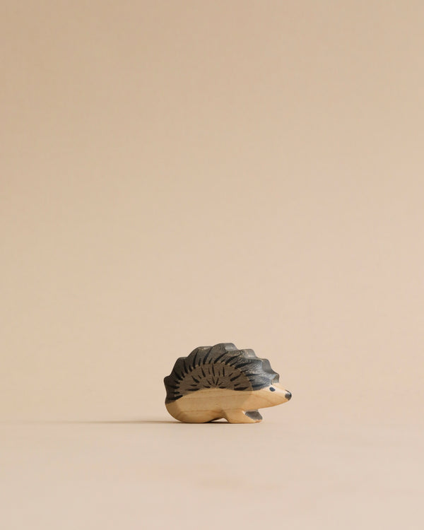 A Handmade Holzwald Hedgehog Mom with intricately carved spines and details, positioned on a smooth beige background. This piece is an example of sustainable, wooden toys.