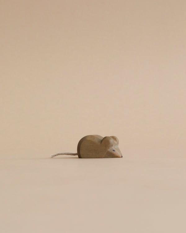 A Handmade Holzwald Mouse figurine with a metallic tail, crafted in the shape of a heart, set against a plain beige background. This piece is one of our sustainable toys.