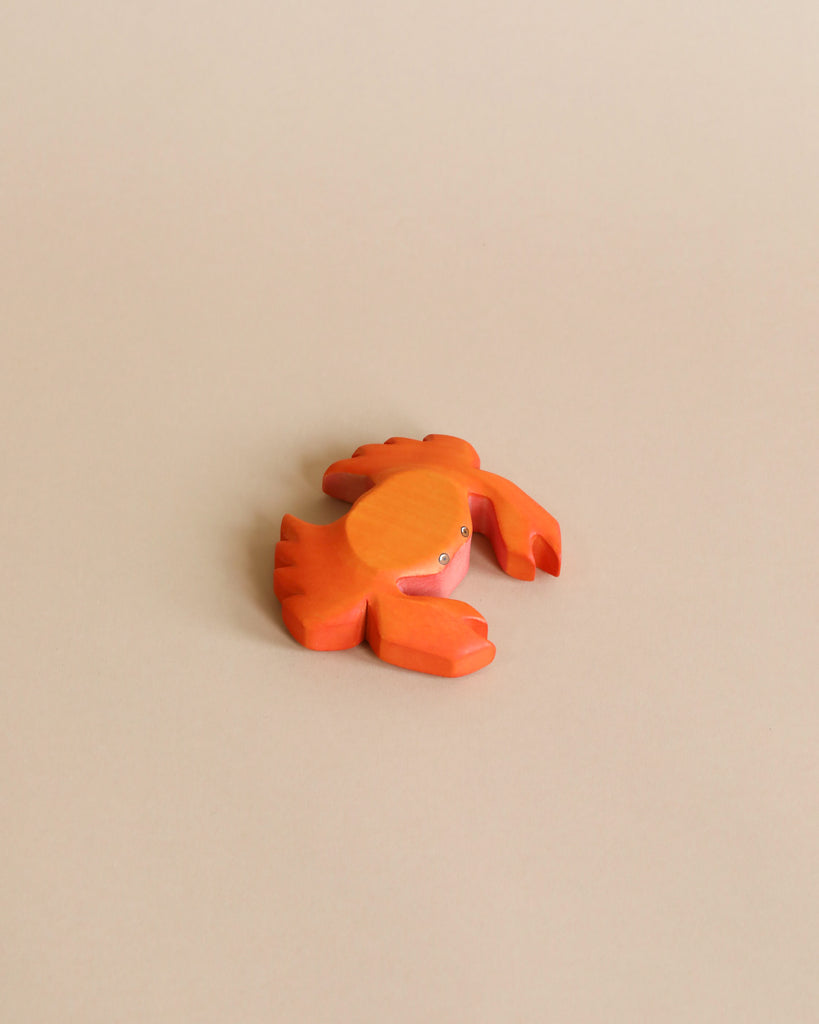 A high-quality Handmade Holzwald Crab with a smiling face and articulated limbs, painted in bright orange, is displayed against a plain beige background.